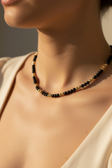 A black matte onyx beaded necklace with 14K yellow gold beads on clear elastic.
