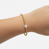 A 3mm yellow gold bracelet with a mother of pearl charm, designed for children.