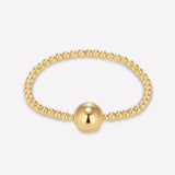 A 4MM 14K yellow gold beaded bracelet with a prominent central bead, featuring a yellow gold bead on clear elastic.