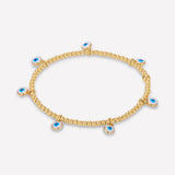 A 2MM 14K yellow gold bracelet for women featuring small yellow gold beads and blue evil eye charms on a clear elastic band.